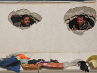 Displaced Palestinians are looking through a hole in the wall of a school after returning to Khan Yunis in the southern Gaza Strip amid the...