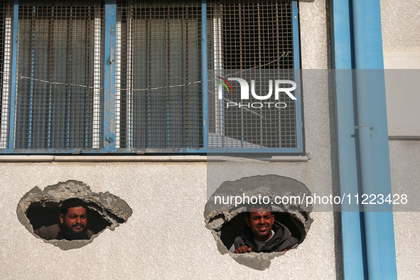 Displaced Palestinians are looking through a hole in the wall of a school after returning to Khan Yunis in the southern Gaza Strip amid the...