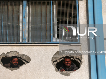 Displaced Palestinians are looking through a hole in the wall of a school after returning to Khan Yunis in the southern Gaza Strip amid the...