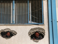 Displaced Palestinians are looking through a hole in the wall of a school after returning to Khan Yunis in the southern Gaza Strip amid the...