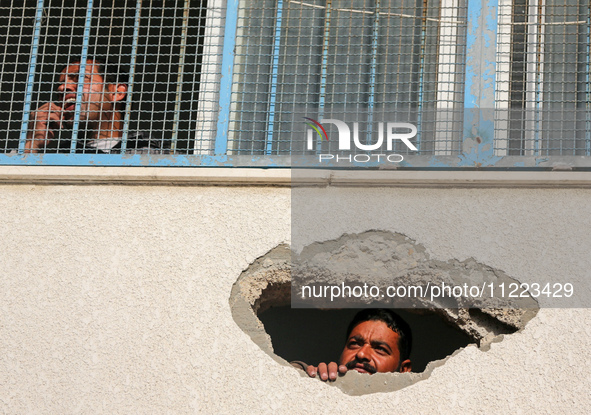 Displaced Palestinians are looking through a hole in the wall of a school after returning to Khan Yunis in the southern Gaza Strip amid the...