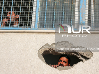 Displaced Palestinians are looking through a hole in the wall of a school after returning to Khan Yunis in the southern Gaza Strip amid the...