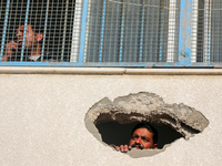 Displaced Palestinians are looking through a hole in the wall of a school after returning to Khan Yunis in the southern Gaza Strip amid the...