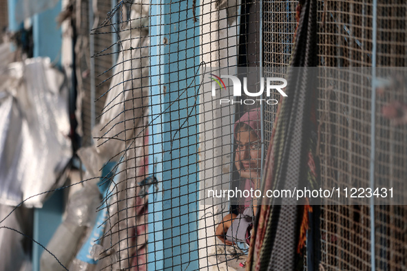 A displaced Palestinian woman is looking out of a school window after returning to Khan Yunis in the southern Gaza Strip, on May 9, 2024, am...