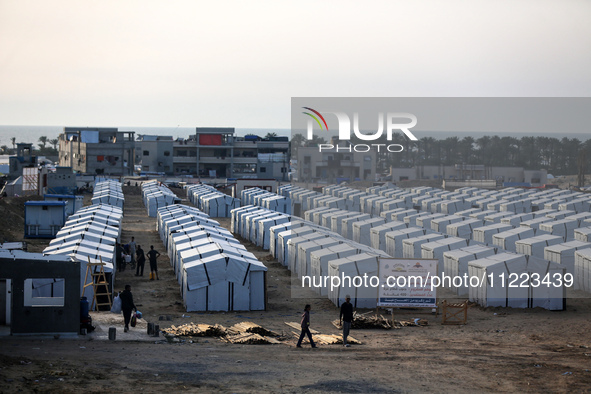 People are walking into a newly-built tent at a camp for displaced Palestinians in Khan Yunis, in the southern Gaza Strip, on May 9, 2024, a...