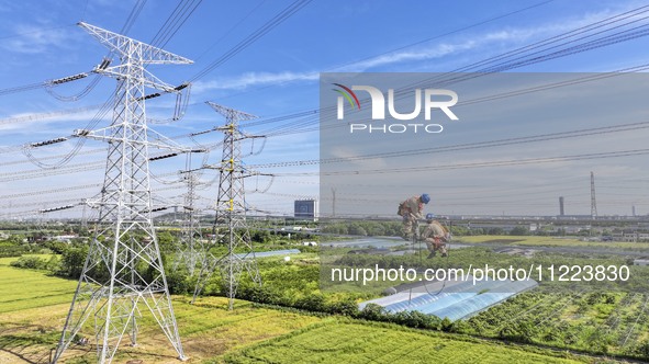 Construction workers are installing spacer rods at a high altitude at the site of a 500-kilovolt line renovation project in Wuxi, Jiangsu Pr...