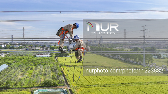 Construction workers are installing spacer rods at a high altitude at the site of a 500-kilovolt line renovation project in Wuxi, Jiangsu Pr...