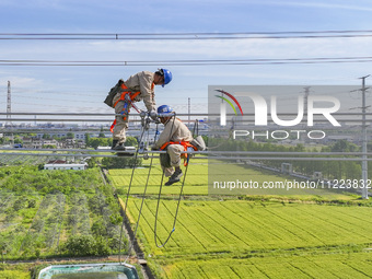 Construction workers are installing spacer rods at a high altitude at the site of a 500-kilovolt line renovation project in Wuxi, Jiangsu Pr...