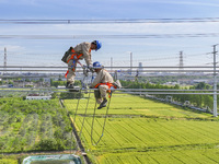 Construction workers are installing spacer rods at a high altitude at the site of a 500-kilovolt line renovation project in Wuxi, Jiangsu Pr...