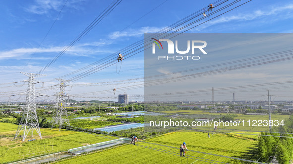 Construction workers are installing spacer rods at a high altitude at the site of a 500-kilovolt line renovation project in Wuxi, Jiangsu Pr...