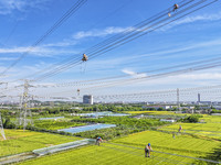 Construction workers are installing spacer rods at a high altitude at the site of a 500-kilovolt line renovation project in Wuxi, Jiangsu Pr...