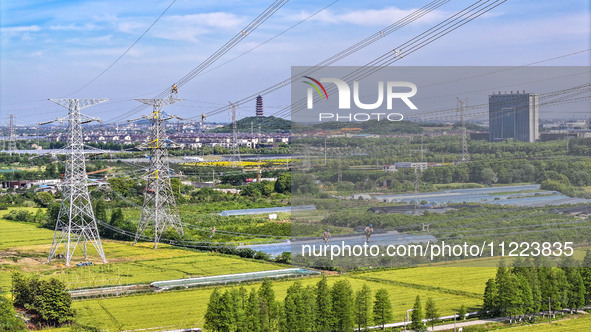 Construction workers are installing spacer rods at a high altitude at the site of a 500-kilovolt line renovation project in Wuxi, Jiangsu Pr...