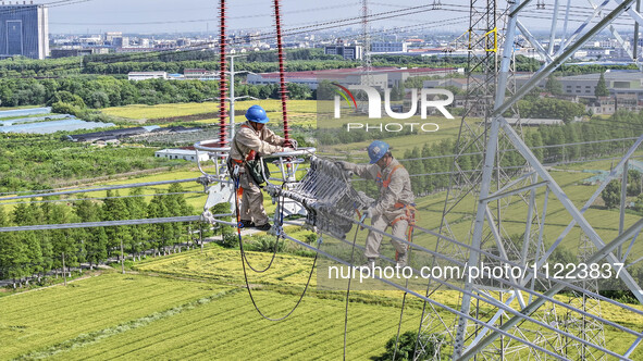 Construction workers are installing spacer rods at a high altitude at the site of a 500-kilovolt line renovation project in Wuxi, Jiangsu Pr...