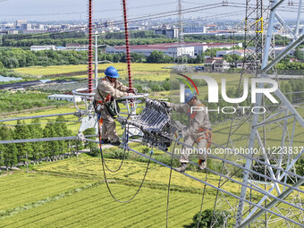 Construction workers are installing spacer rods at a high altitude at the site of a 500-kilovolt line renovation project in Wuxi, Jiangsu Pr...