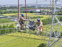 Construction workers are installing spacer rods at a high altitude at the site of a 500-kilovolt line renovation project in Wuxi, Jiangsu Pr...