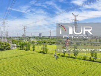 Construction workers are installing spacer rods at a high altitude at the site of a 500-kilovolt line renovation project in Wuxi, Jiangsu Pr...