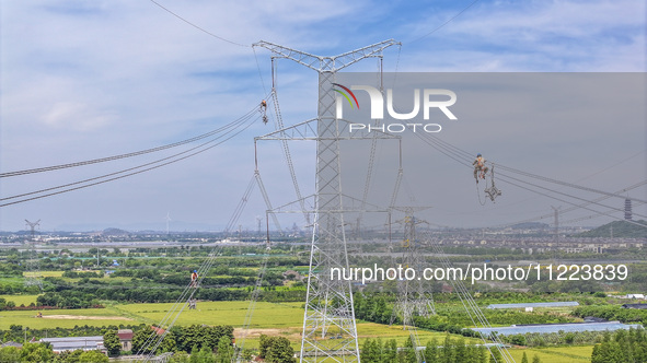 Construction workers are installing spacer rods at a high altitude at the site of a 500-kilovolt line renovation project in Wuxi, Jiangsu Pr...