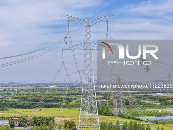 Construction workers are installing spacer rods at a high altitude at the site of a 500-kilovolt line renovation project in Wuxi, Jiangsu Pr...