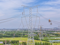 Construction workers are installing spacer rods at a high altitude at the site of a 500-kilovolt line renovation project in Wuxi, Jiangsu Pr...