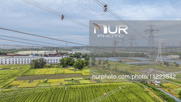 Construction workers are installing spacer rods at a high altitude at the site of a 500-kilovolt line renovation project in Wuxi, Jiangsu Pr...