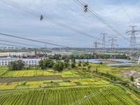 Construction workers are installing spacer rods at a high altitude at the site of a 500-kilovolt line renovation project in Wuxi, Jiangsu Pr...