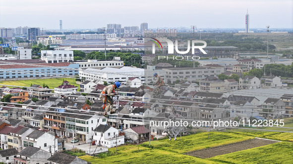 Construction workers are installing spacer rods at a high altitude at the site of a 500-kilovolt line renovation project in Wuxi, Jiangsu Pr...