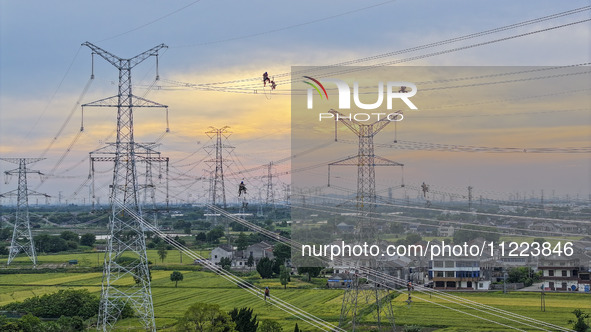 Construction workers are installing spacer rods at a high altitude at the site of a 500-kilovolt line renovation project in Wuxi, Jiangsu Pr...