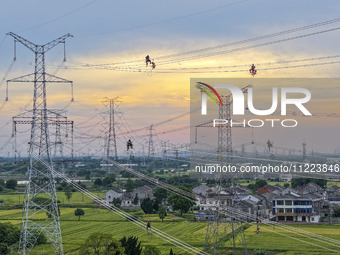 Construction workers are installing spacer rods at a high altitude at the site of a 500-kilovolt line renovation project in Wuxi, Jiangsu Pr...