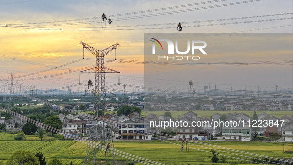 Construction workers are installing spacer rods at a high altitude at the site of a 500-kilovolt line renovation project in Wuxi, Jiangsu Pr...