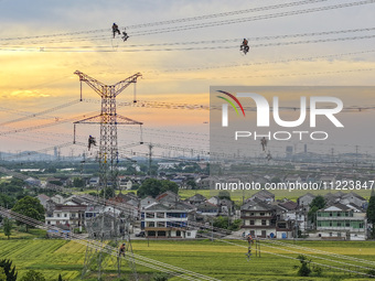 Construction workers are installing spacer rods at a high altitude at the site of a 500-kilovolt line renovation project in Wuxi, Jiangsu Pr...