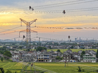 Construction workers are installing spacer rods at a high altitude at the site of a 500-kilovolt line renovation project in Wuxi, Jiangsu Pr...