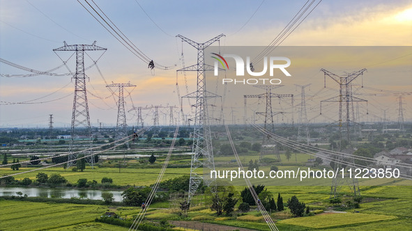 Construction workers are installing spacer rods at a high altitude at the site of a 500-kilovolt line renovation project in Wuxi, Jiangsu Pr...