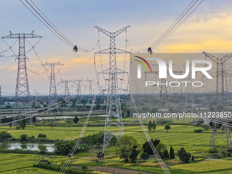 Construction workers are installing spacer rods at a high altitude at the site of a 500-kilovolt line renovation project in Wuxi, Jiangsu Pr...