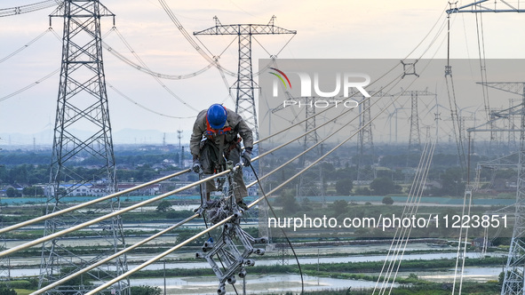 Construction workers are installing spacer rods at a high altitude at the site of a 500-kilovolt line renovation project in Wuxi, Jiangsu Pr...