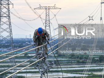 Construction workers are installing spacer rods at a high altitude at the site of a 500-kilovolt line renovation project in Wuxi, Jiangsu Pr...