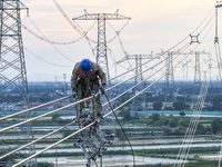 Construction workers are installing spacer rods at a high altitude at the site of a 500-kilovolt line renovation project in Wuxi, Jiangsu Pr...