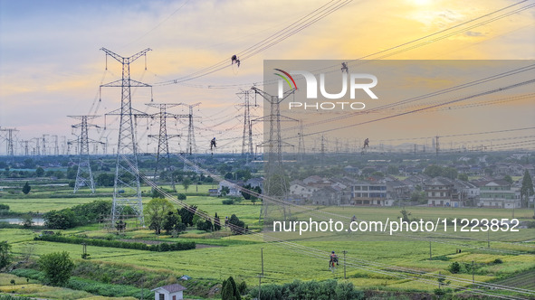 Construction workers are installing spacer rods at a high altitude at the site of a 500-kilovolt line renovation project in Wuxi, Jiangsu Pr...