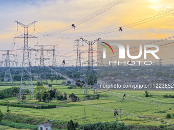 Construction workers are installing spacer rods at a high altitude at the site of a 500-kilovolt line renovation project in Wuxi, Jiangsu Pr...