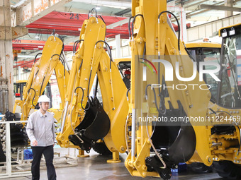 A manager is walking in front of an excavator at the production line of LOVOL Co in Qingdao, Shandong Province, China, on May 9, 2024. (