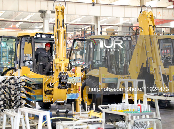 Workers are debugging an excavator on the production line of LOVOL Co in Qingdao, Shandong Province, China, on May 9, 2024. 