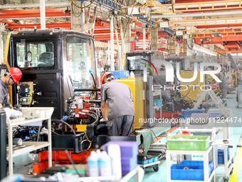 Workers are operating excavators on a production line at LOVOL Co in Qingdao, Shandong province, China, on May 9, 2024. (