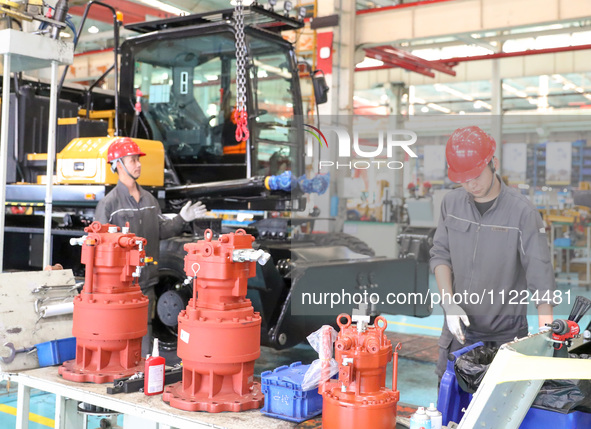 Workers are lifting spare parts at a production line of LOVOL Co in Qingdao, Shandong province, China, on May 9, 2024. 