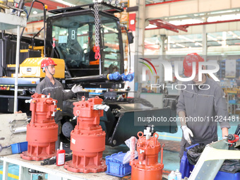 Workers are lifting spare parts at a production line of LOVOL Co in Qingdao, Shandong province, China, on May 9, 2024. (