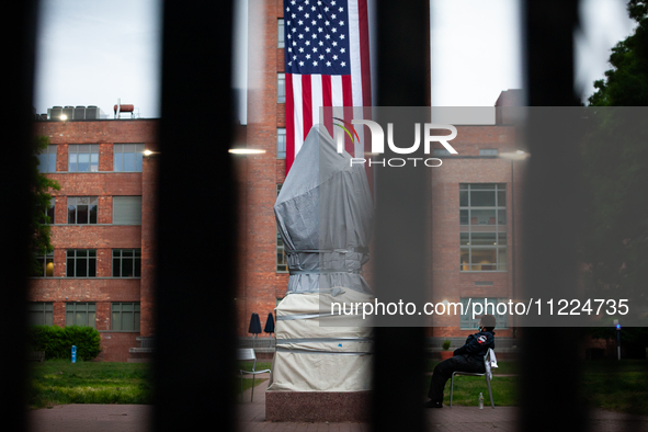 A security guard sits next to the Statue of George Washington behind a tall, "unscaleable" fence following the clearing of the Gaza solidari...