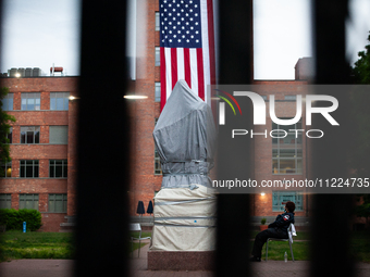 A security guard sits next to the Statue of George Washington behind a tall, "unscaleable" fence following the clearing of the Gaza solidari...