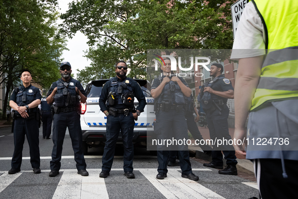 A protest marshal faces a line of DC police as George Washington University students and their supporters rally at the site of their Gaza so...