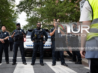 A protest marshal faces a line of DC police as George Washington University students and their supporters rally at the site of their Gaza so...