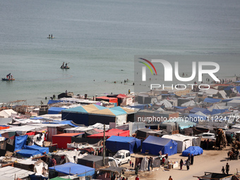 Tents housing internally displaced Palestinians are crowding the beach and the Mediterranean shoreline in Deir el-Balah in the central Gaza...