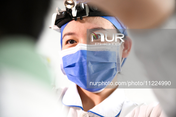 A nurse is performing an external ear canal examination on a hospitalized child at the otolaryngology department of Jiangxi Children's Hospi...