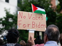 A demonstrator carries a sign in opposing President Joe Biden's re-election during a rally at the site of the George Washington university G...